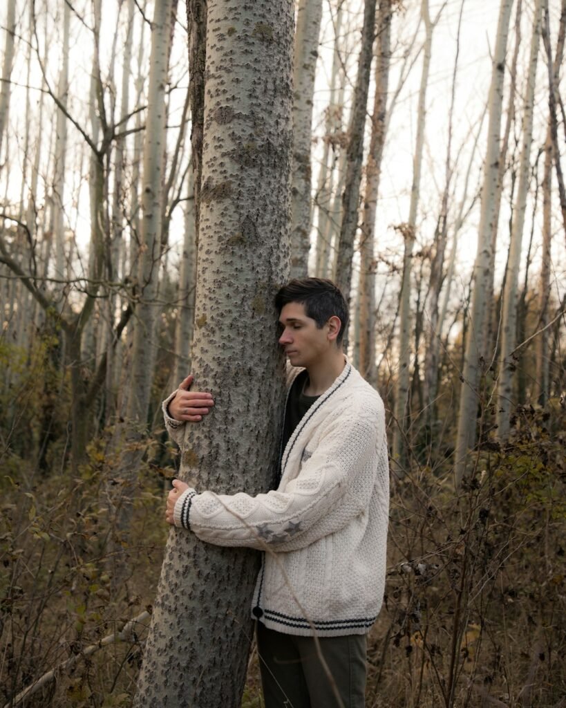 Jovan Vasiljević Photography | There is no plan(et) B | A young man wearing a knitted cardigan hugging a tree in the middle of a forest