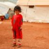 A young child standing in front of a tent